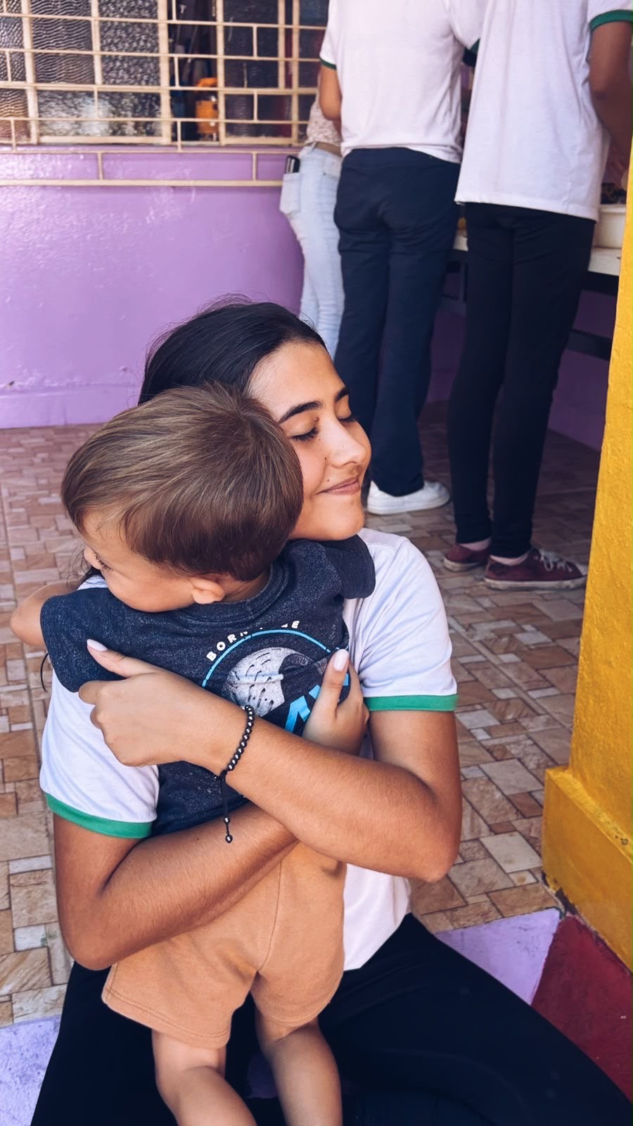 Voluntária do projeto abraçando um menino durante uma visita