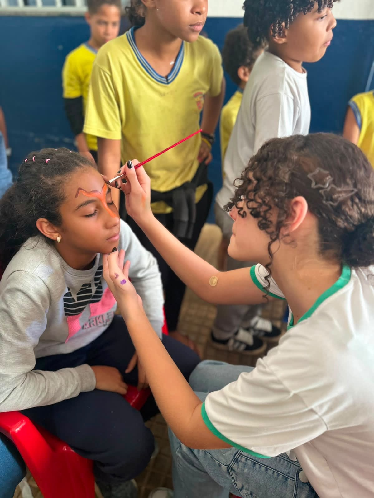 Voluntária pintando o rosto de uma criança durante atividade do projeto